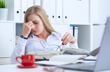 Tired Caucasian businesswoman holding eyeglasses and massaging nose bridge. Girl feeling discomfort...