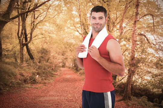 Fit man smiling at camera against peaceful autumn scene in forest