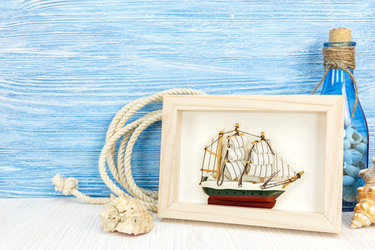 maritime background with sea shells, picture frame, ship and bottle on weathered blue wood 