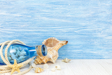 Fototapeta na wymiar summer travel background with seashells, blue glass bottle and marine rope on weathered boards 