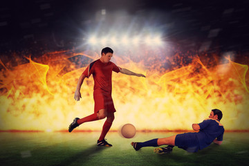 Obraz na płótnie Canvas Football players tackling for the ball against football pitch under spotlights