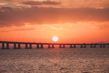 Fototapeta na wymiar Orange sunset over the bridge silhouette. Ocean hrizon sunny landscape