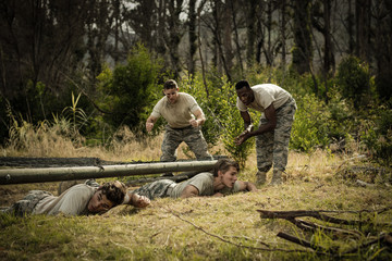 Soldiers crawling under the net during obstacle course - Powered by Adobe