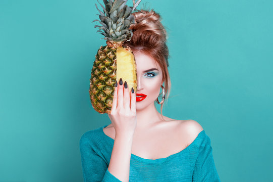 Tasty tropical fruits! Attractive sexual woman with beautiful makeup holding fresh juicy pineapple and looking at cam on isolated blue background. Summer Fashion Lifestyle Creative Healthy Food