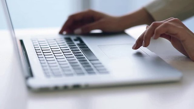 Business girl with beautiful hands typing on keyboard, running on laptop. Writes the text, communicates in messengers and edits articles. A beautiful light and bokeh on the hands of.
