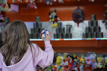 Child from behind throwing balls at cans at the amusement park in Leipzig, Germany (Kleinmesse)