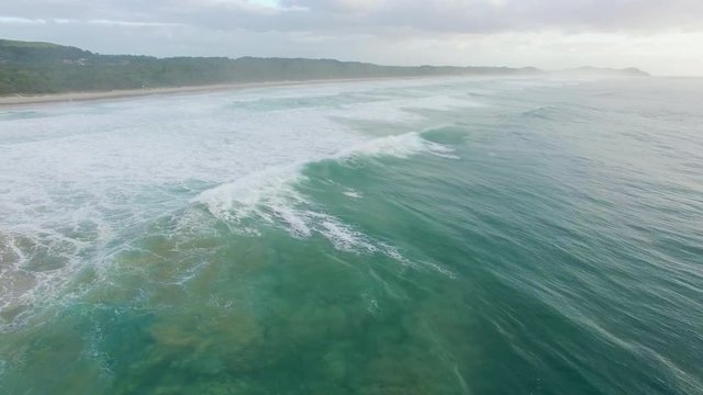 Aerial pan across powerful crushing ocean waves near the coastline in Australia
