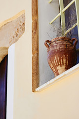Clay pot with dried flowers stands on the window outside the ancient house as a decoration
