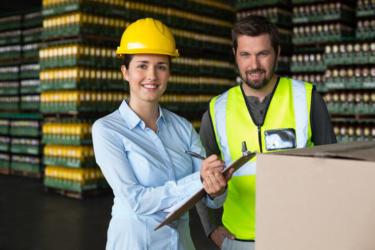 Factory workers maintaining record on clipboard in factory - Powered by Adobe