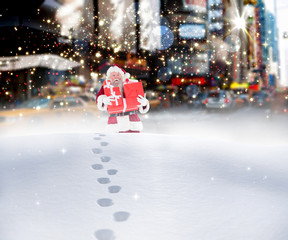 Santa carrying gifts in the snow against blurry new york street