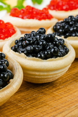 Homemade tartlets with red and black caviar. Food background. Concept of luxury food. Vertical.