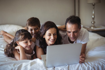 Happy family using laptop on bed in bedroom