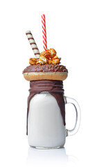 Crazy milk shake with chocolate donut, caramel popcorn and straw in glass jar
