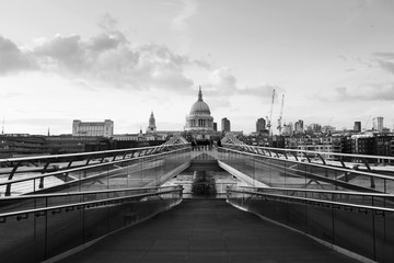 Millennium bridge with Saint Paul Cathedral in the evening in London, UK. Bridge over river Thames. Black and white