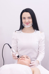 Microcurrent therapy for the face. Cosmetic procedure. Young girl beautician