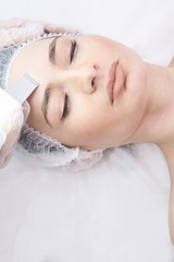 Fototapeta na wymiar Modern equipment. Cosmetic procedure. Ultrasonic cleaning of the face.Young girl