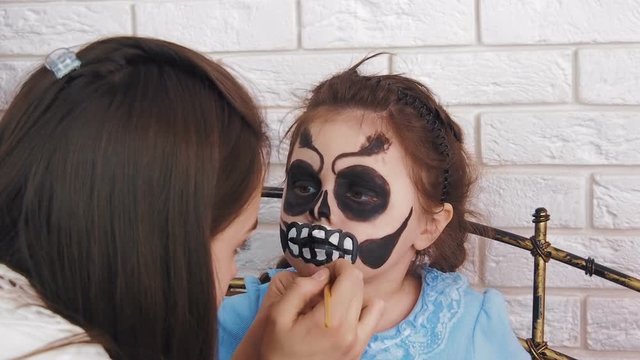 Makeup to the child. Draw on the face. Child on Halloween.