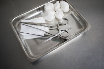 Gauze, Orthopedic Bandage,Cotton Swab, Tissue Forceps and Scissors on the Medical Stainless Steel Tray for Wound Dressing on the medical table