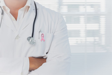 Doctor with arms folded wearing breast cancer awareness ribbon
