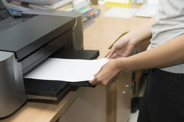 Naklejka na ściany i meble woman inserting paper sheet on a printer tray waiting to feed for printing a job by hand
