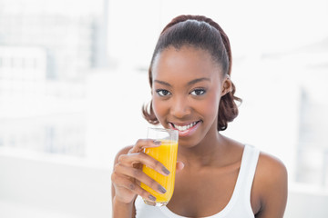 Happy sporty model holding glass of orange juice