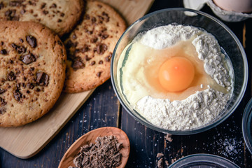 Chocolate cookies on wooden table with flour eggs and ingredients