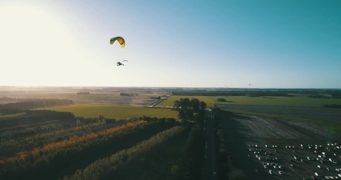parapente volando sobre plantas y autos