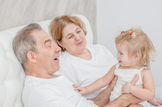 Grandparents and baby girl having fun on the bed