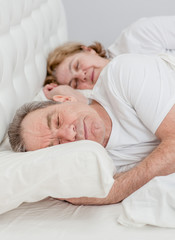Elderly couple sleeping together on the bed