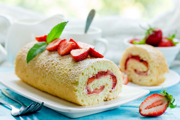 Sweet roll stuffed with strawberry and cream decorated with strawberries, powdered sugar and mint...