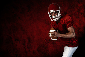 Player holding rugby ball and posing against dark background