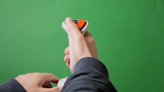 Playing with a retro vintage joystick (input device for computer games) over a green background. Back view.
