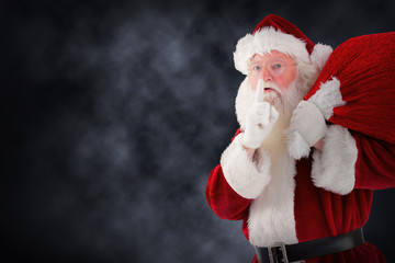 Santa claus carrying sack against blue background with vignette