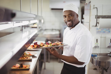 Chef holding dessert tray in commercial kitchen