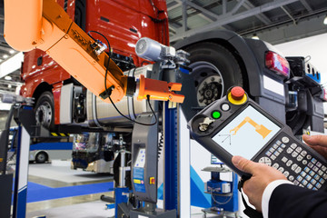 Engineer with teach pendant device. Programming robot with robotic arm at a car service or assembly...