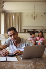 Portrait of man with laptop sitting in living room