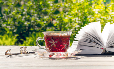 Peaceful holiday in a sunny garden. A cup and a book for reading
