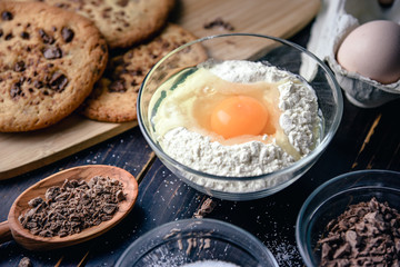 Chocolate cookies on wooden table with flour eggs and ingredients