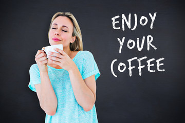 Peaceful blonde with hot beverage relaxing against black background