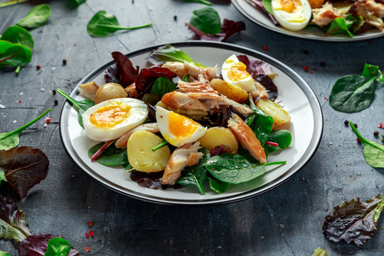 Warm Smoked Mackerel Salad with new potato, eggs, green lettuce mix in a plate.