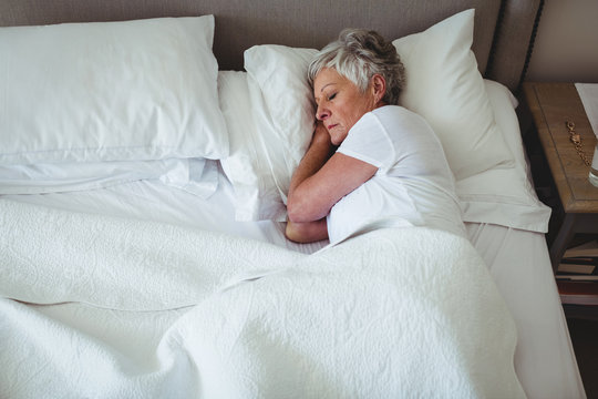 Senior woman sleeping on bed in bedroom