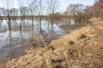 Plastic trash on the river bank floating during the spring flood in spring
