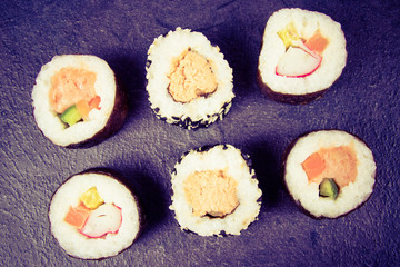 Various kinds of sushi on the dark background.