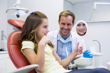 Smiling young patient looking in the mirror in dental clinic 