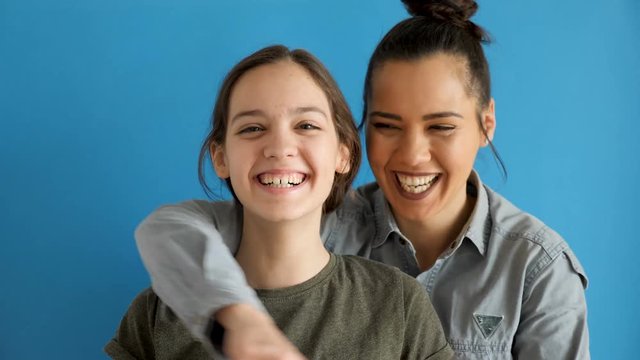 Younger sisters standing in the front while the oldes is embracing her from the back. Slow motion footage. Blue background