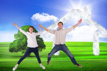 Fototapeta na wymiar Couple jumping and holding hands against sunny green landscape