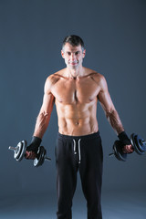 Fototapeta na wymiar Handsome muscular man working out with dumbbells. Personal fitness instructor. Personal training.