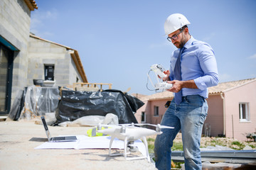 handsome architect flying inspection drone for aerial view of a house construction site industry