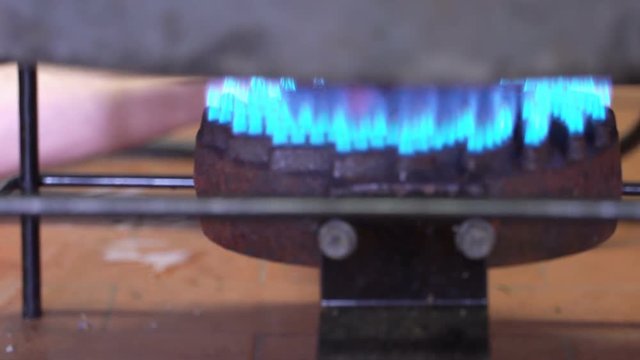 Production of perfume essences using steam in a distillation cube in a small alpine village. An elderly man heats the distillation apparatus with a gas burner. Real people.