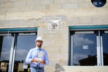 handsome architect flying inspection drone for aerial view of a house construction site industry